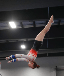 "Alumni spotlight profile for Meagan Beffort. To the left, an action shot captures her mid-air in a layout position during a vault or floor pass, wearing a red and white gradient leotard. To the right, a candid photo shows Meagan as a coach in a gymnasium, wearing a white t-shirt, black hat, and red sunglasses. The accompanying text details her journey from a Level 8 gymnast to a Summer Camp Director and current Health Science student.