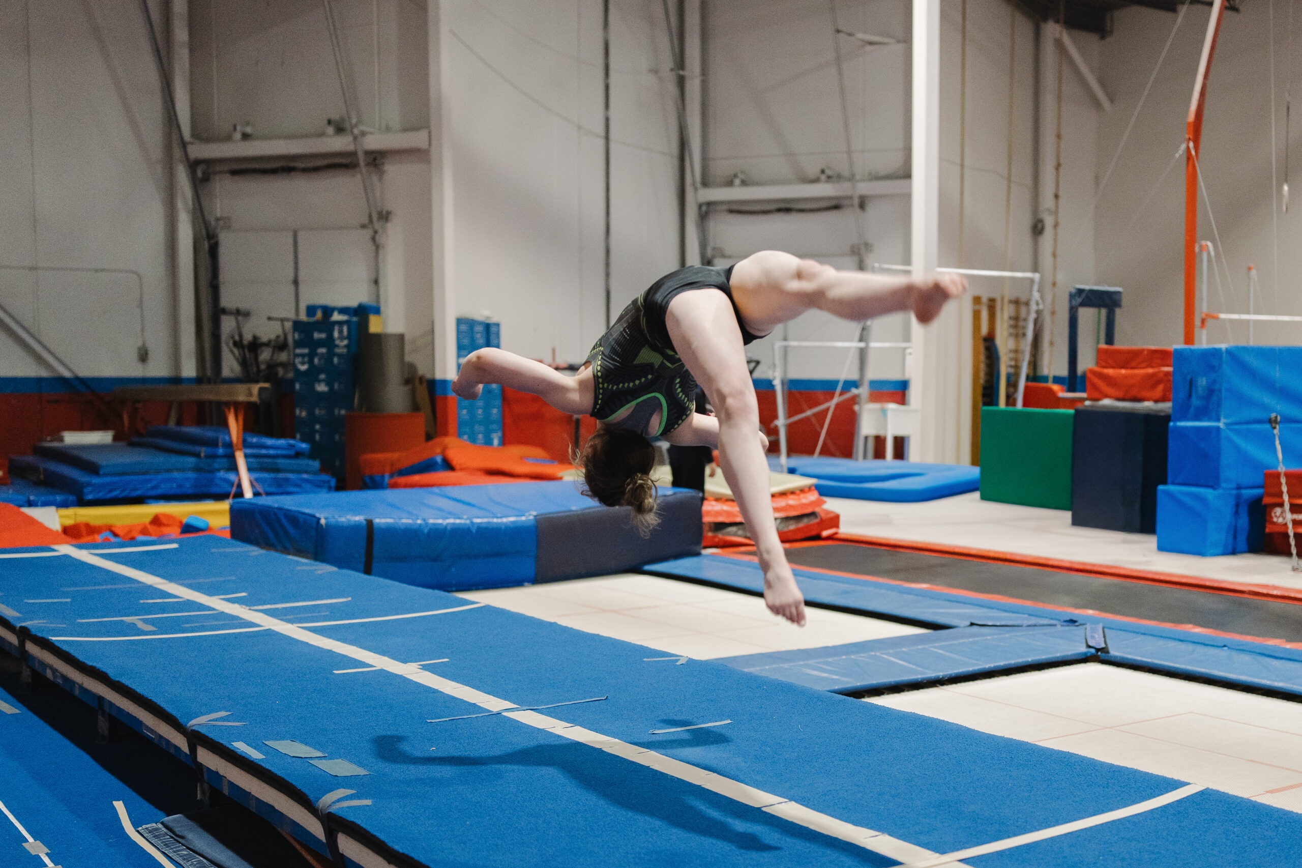 A gymnast in a red leotard performing a back handspring on a blue floor mat for the All Star Tumbling Program introduction section.