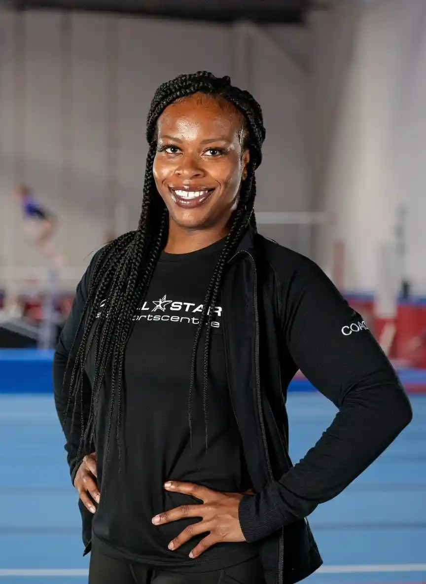 A professional headshot of Coach Roxanne smiling in a black team athletic shirt.