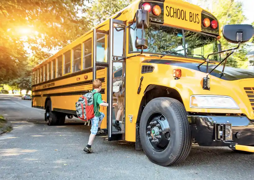 A young student with a backpack boarding a classic yellow school bus for a field trip.