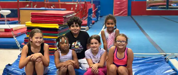 Group of young gymnasts huddling and laughing. Text: "Strong Teams. Stronger Friendships. Join the All Star Family Today."