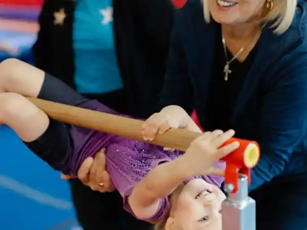 Toddler practicing bars with parent in Lit’l Monkeys gymnastics (18–36 months).